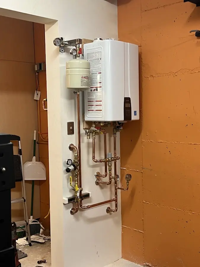 Plumbing technician inspecting water heater connections in Hollis